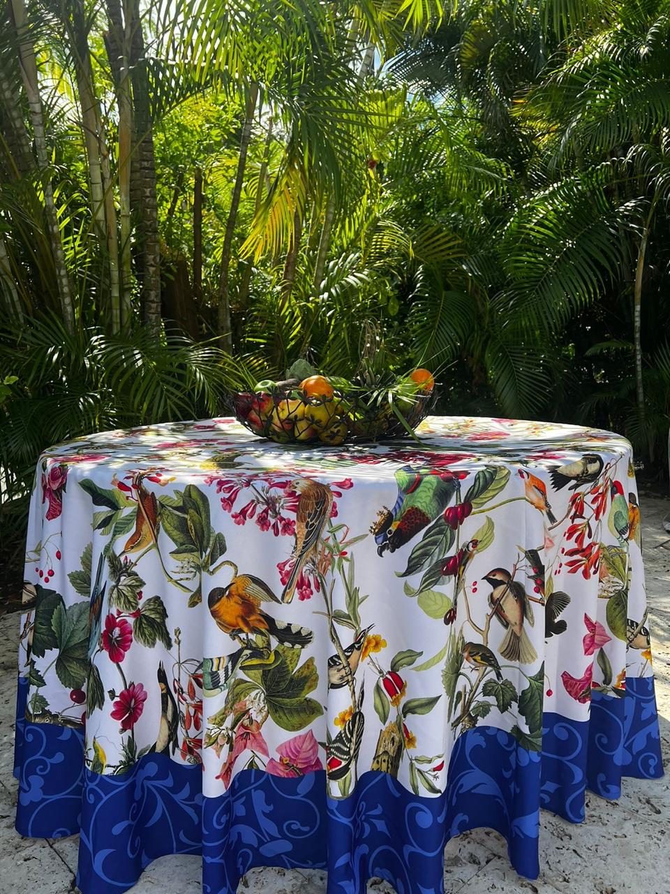 Mesa redonda en el jardín con mantel de aves tropicales
